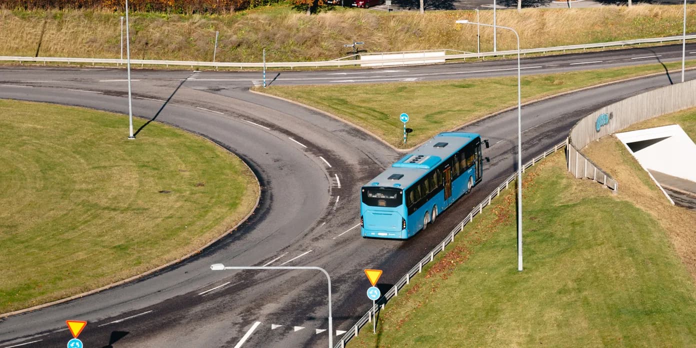 En blå buss som kör på en kurvig väg