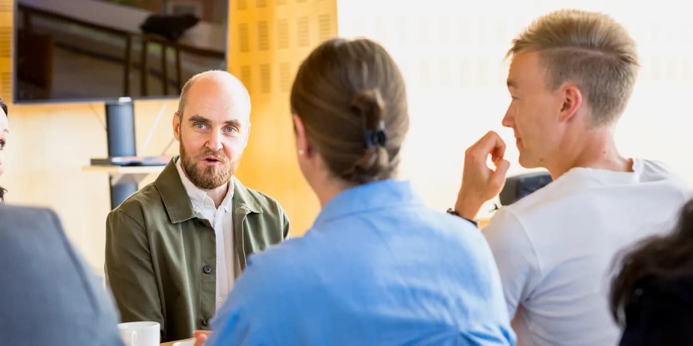 En grupp människor som sitter runt ett bord och pratar