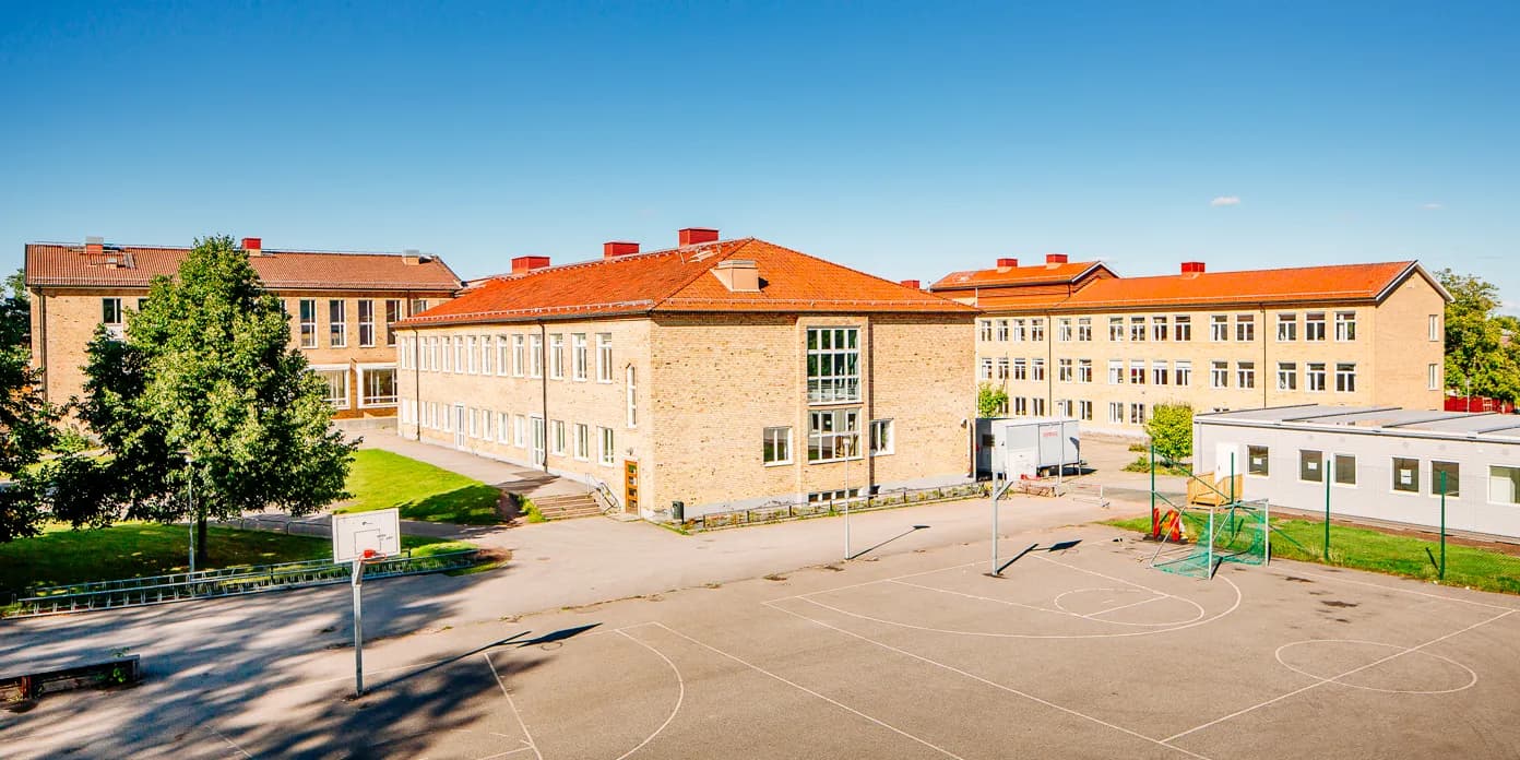 En basketplan framför en stor gul tegelbyggnad