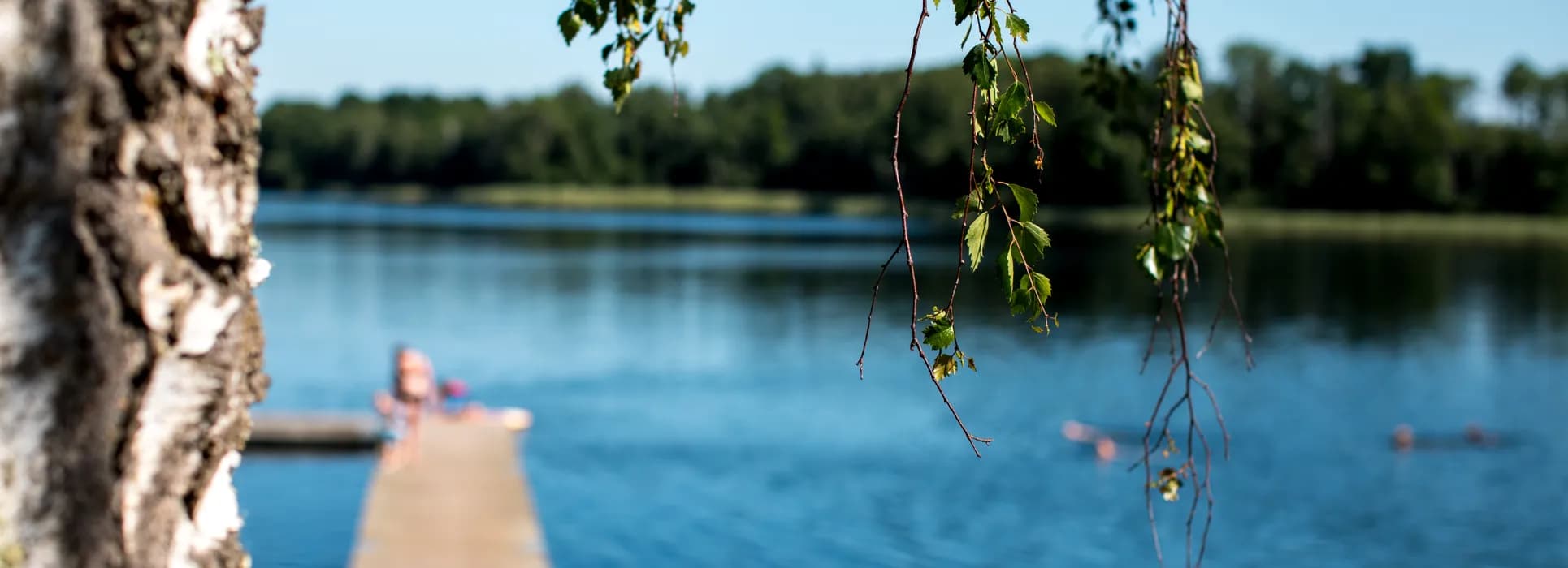 Personer på en brygga vid en blank sjö.