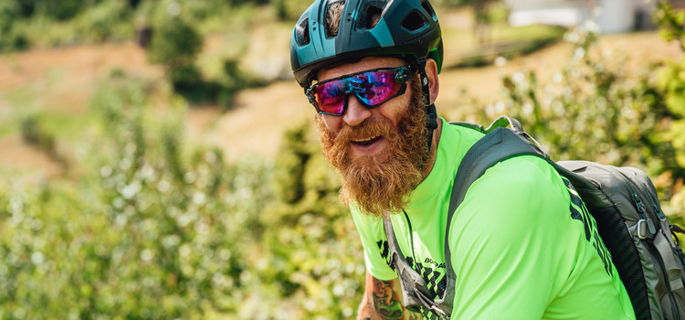 Picture of a smiling man with a big red beard. He has a bicycle helmet on his head.