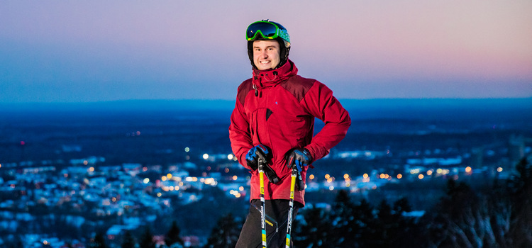 Picture of a guy standing on top of the slalom slope in Skövde. He is wearing a ski helmet and a red jacket.