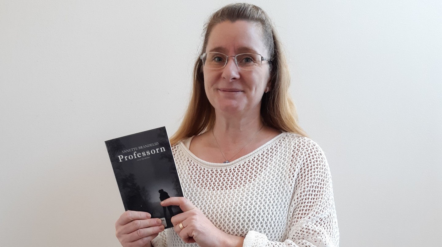 Annette Brandelid håller upp sin bok Professorn 