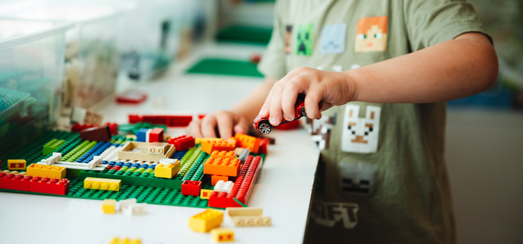 En liten pojke leker med bilar och bygger med lego